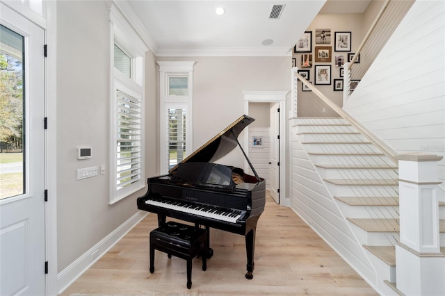 living area with stairway, baseboards, visible vents, light wood-style flooring, and ornamental molding