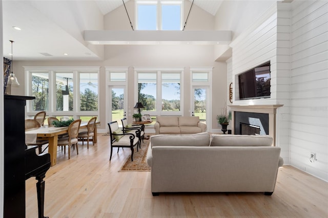 living room with recessed lighting, light wood-type flooring, high vaulted ceiling, and a fireplace