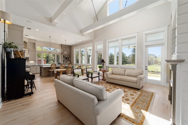 living room with visible vents, recessed lighting, light wood-type flooring, and a towering ceiling