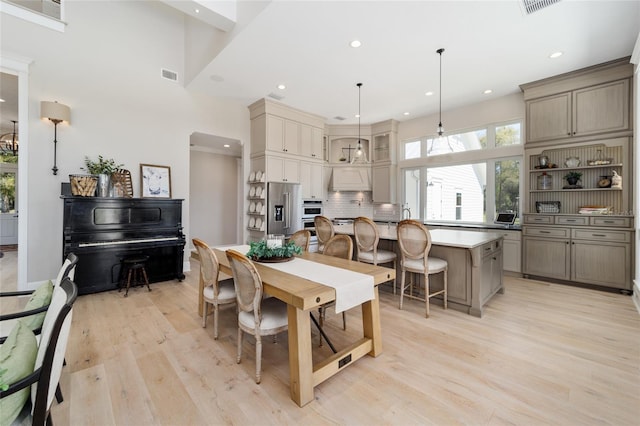 dining room featuring visible vents, recessed lighting, light wood-style floors, and a towering ceiling