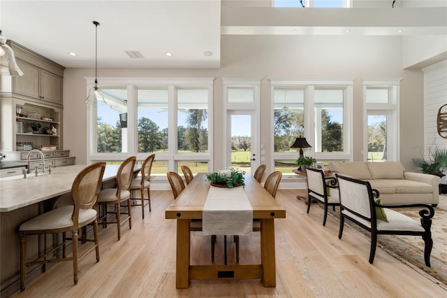 dining room featuring a healthy amount of sunlight, a high ceiling, and light wood-style floors