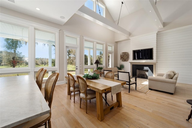 dining area featuring recessed lighting, a fireplace, high vaulted ceiling, and light wood-type flooring