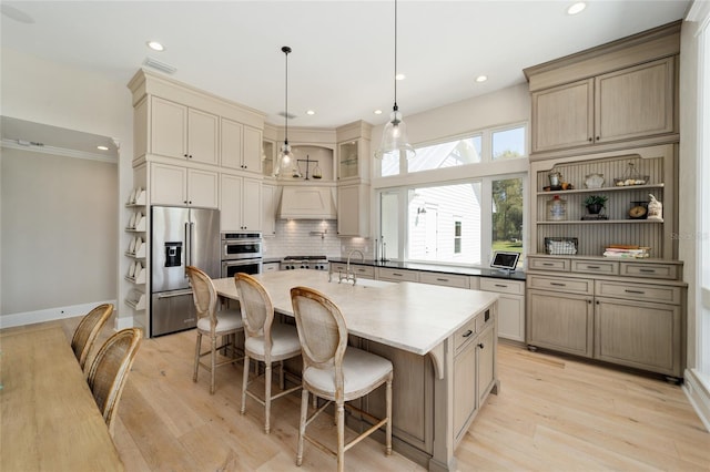 kitchen featuring visible vents, backsplash, an island with sink, custom range hood, and stainless steel appliances