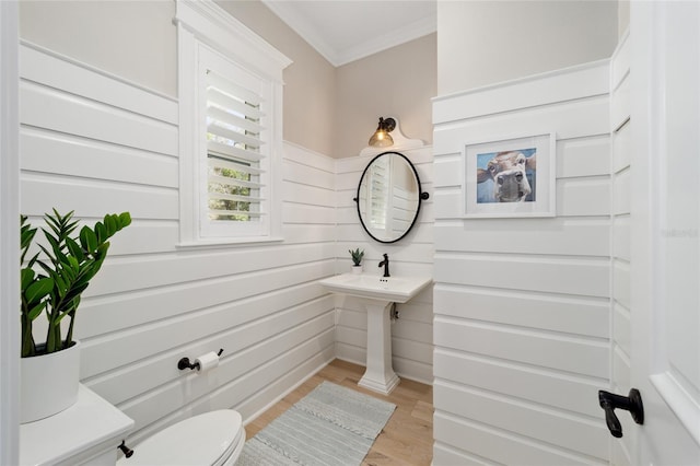 half bath featuring wood finished floors, toilet, and ornamental molding