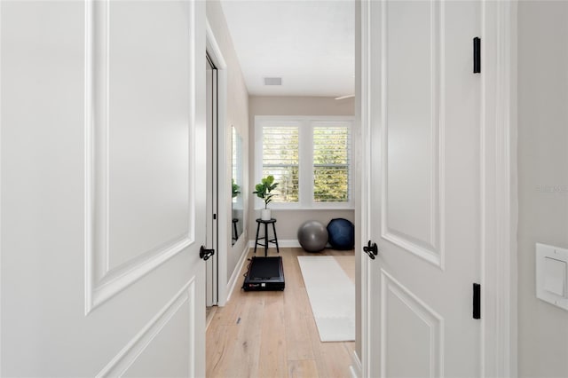 hall featuring visible vents, light wood-style flooring, and baseboards