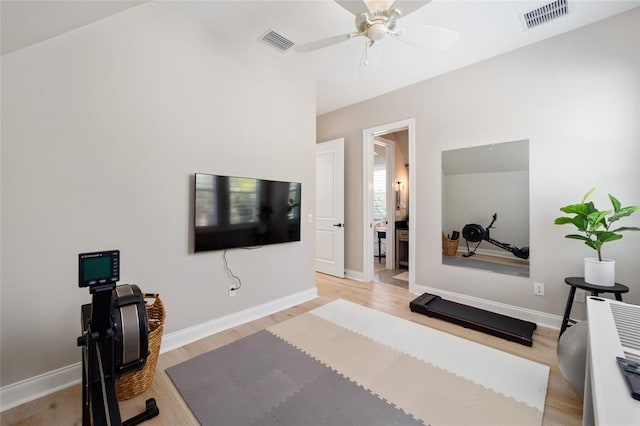 exercise room featuring light wood finished floors, visible vents, and ceiling fan