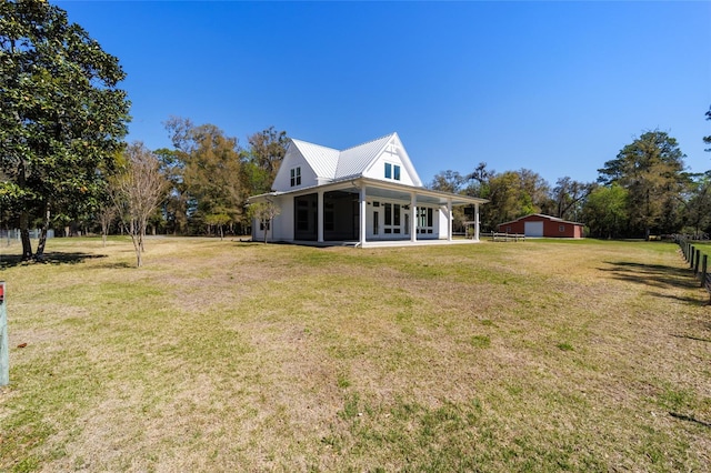 rear view of house with a lawn, metal roof, and a sunroom