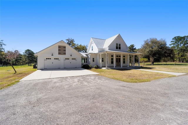 view of front of property with a front lawn, covered porch, metal roof, a garage, and driveway