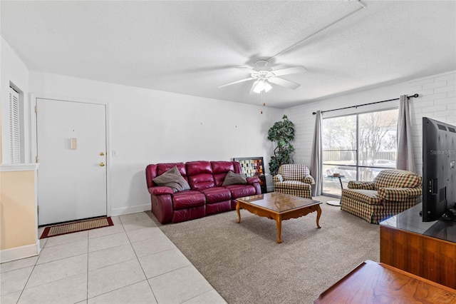 living area with light tile patterned floors, a ceiling fan, baseboards, and a textured ceiling