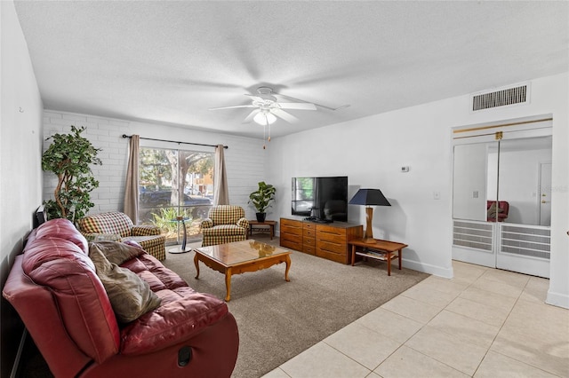 tiled living room featuring baseboards, a ceiling fan, visible vents, and a textured ceiling