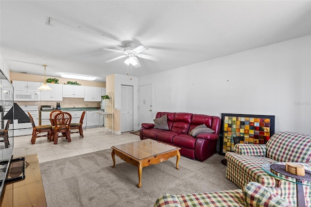 living area featuring light tile patterned floors, light carpet, a textured ceiling, and a ceiling fan