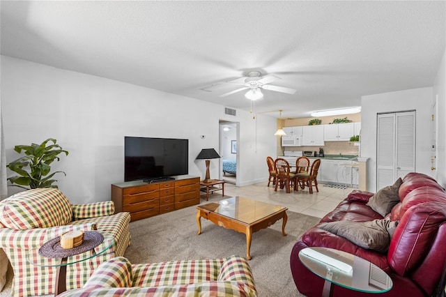 living area with light tile patterned flooring, visible vents, a textured ceiling, and ceiling fan