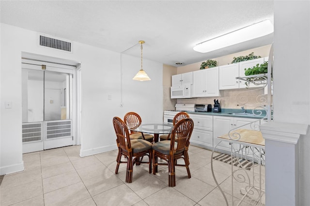 dining room featuring a toaster, light tile patterned floors, baseboards, and visible vents