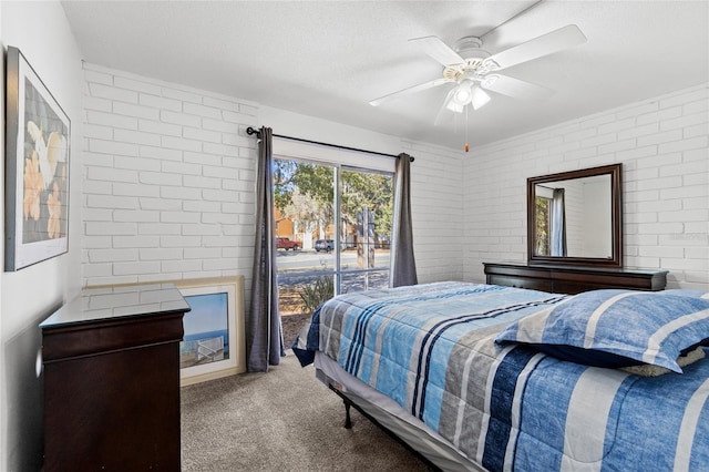 carpeted bedroom with a textured ceiling, brick wall, and a ceiling fan