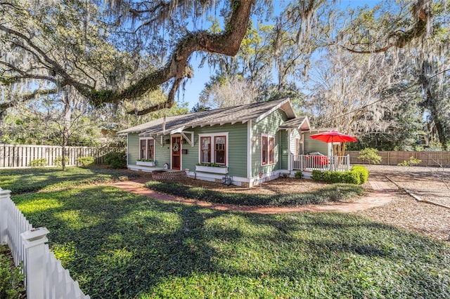 view of front facade with a fenced backyard, a wooden deck, and a front yard