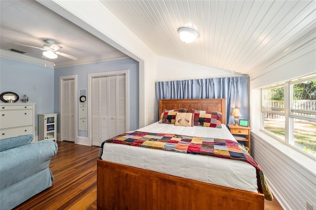 bedroom featuring visible vents, multiple closets, lofted ceiling, ornamental molding, and wood finished floors