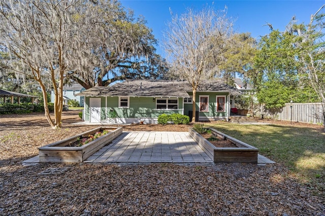 back of property featuring a lawn, a vegetable garden, and fence