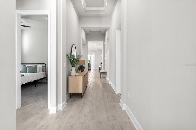 hall with baseboards and light wood finished floors