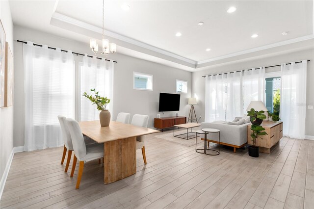 dining room featuring a tray ceiling, light wood-type flooring, and a chandelier