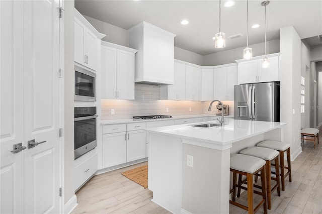 kitchen featuring tasteful backsplash, a kitchen bar, light countertops, stainless steel appliances, and a sink