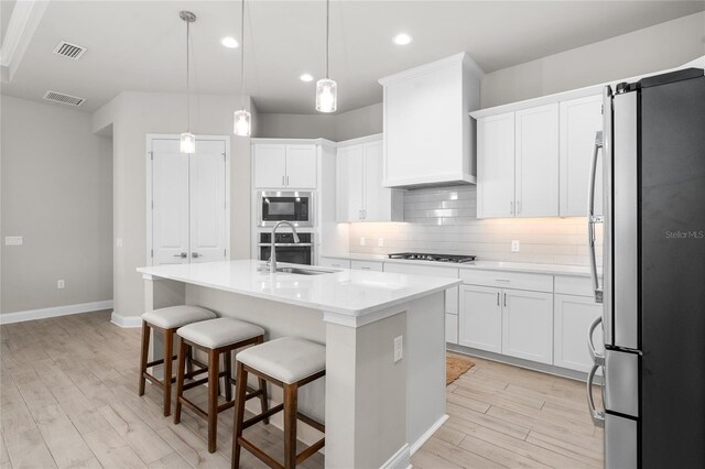 kitchen with visible vents, custom range hood, backsplash, appliances with stainless steel finishes, and light countertops