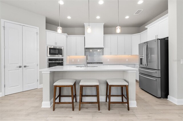 kitchen with visible vents, appliances with stainless steel finishes, light countertops, and a kitchen breakfast bar