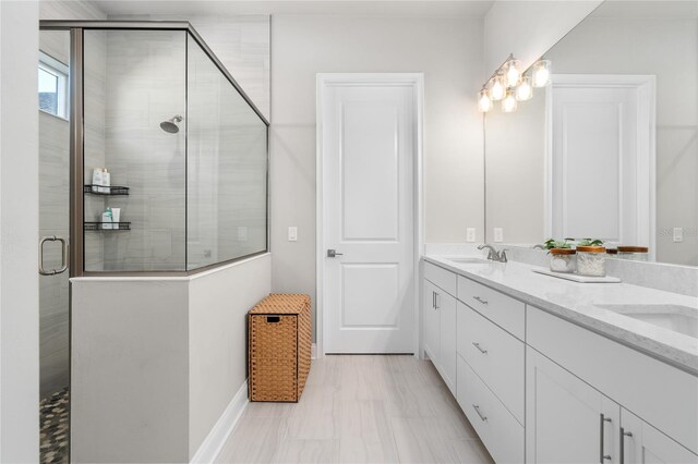 bathroom with a sink, tiled shower, and double vanity