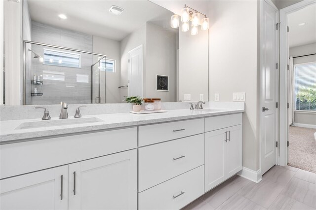 bathroom featuring a sink, baseboards, double vanity, and a shower stall