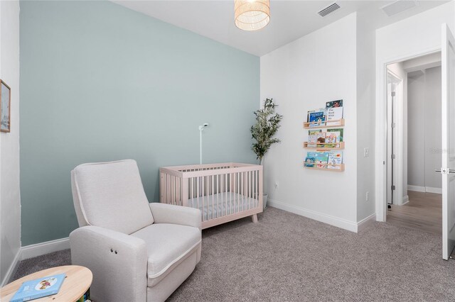 carpeted bedroom featuring a crib, baseboards, and visible vents