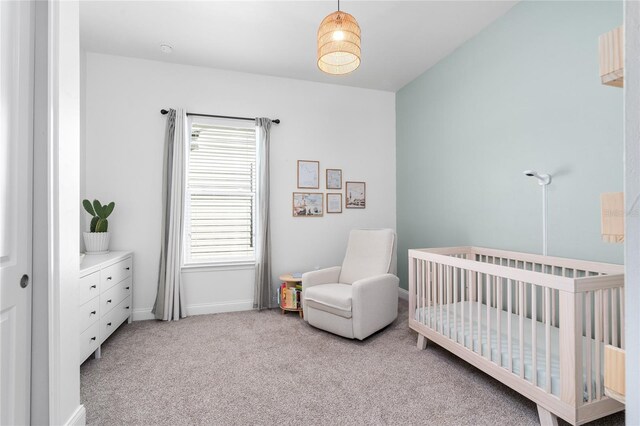 carpeted bedroom with a crib and baseboards