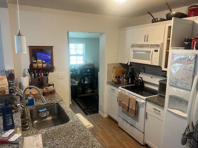 kitchen with white appliances, white cabinets, wood finished floors, and a sink