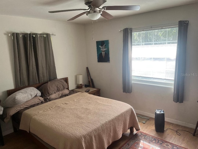 bedroom with wood finished floors, baseboards, and ceiling fan