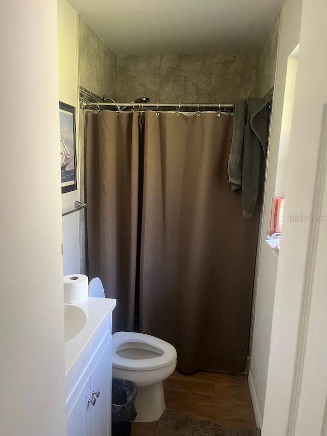 bathroom with a shower with curtain, toilet, wood finished floors, and vanity