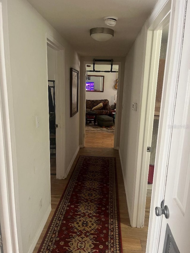 hall featuring light wood-type flooring and baseboards