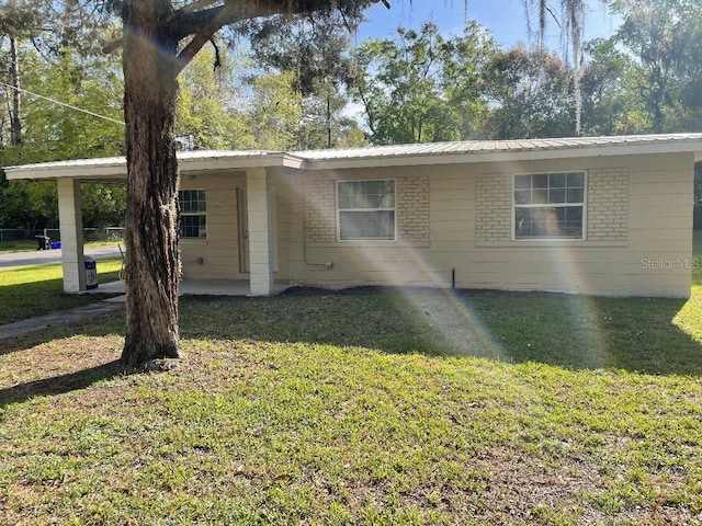 view of front facade featuring an attached carport, a front yard, and metal roof