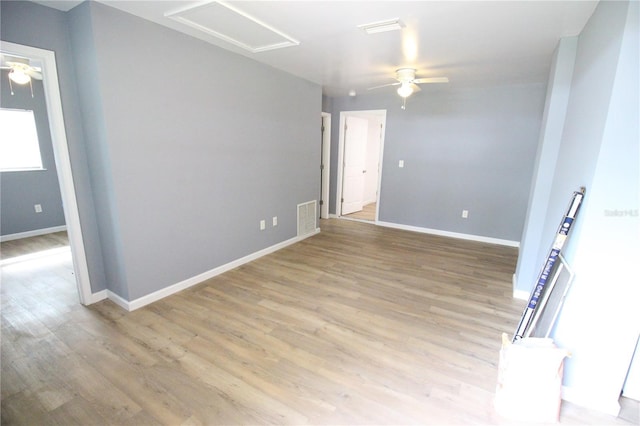 unfurnished room featuring visible vents, light wood-style flooring, baseboards, attic access, and ceiling fan