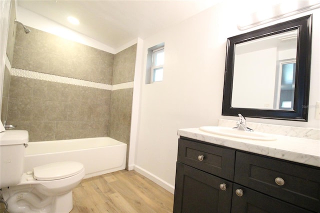 bathroom featuring baseboards, toilet, vanity, wood finished floors, and washtub / shower combination