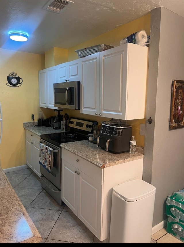 kitchen with visible vents, white cabinetry, appliances with stainless steel finishes, light tile patterned flooring, and light countertops