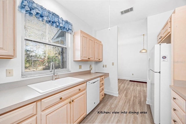 kitchen with visible vents, light brown cabinetry, a sink, white appliances, and light countertops