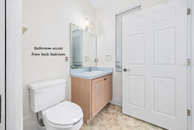 bathroom featuring toilet, vanity, and baseboards