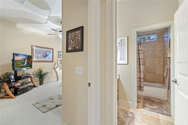 hallway with visible vents, light colored carpet, and baseboards