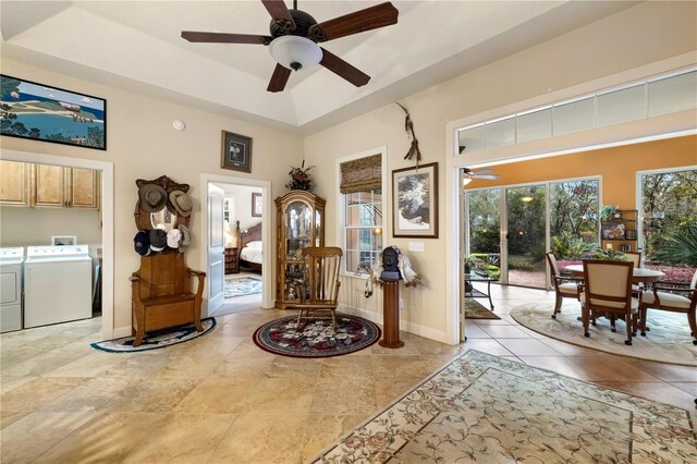 foyer with a ceiling fan, baseboards, washing machine and clothes dryer, a towering ceiling, and a raised ceiling