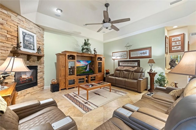 living area with a ceiling fan, a fireplace, visible vents, and baseboards