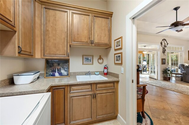 kitchen with brown cabinetry, light countertops, a ceiling fan, and a sink