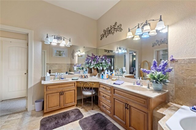 full bathroom with double vanity, a bathtub, tile walls, and a sink