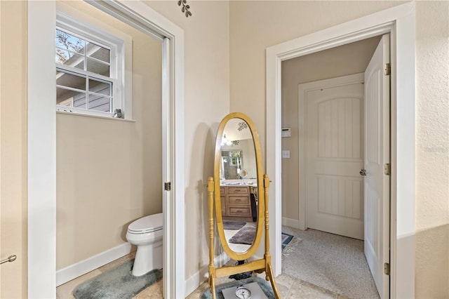 bathroom with toilet, vanity, and baseboards