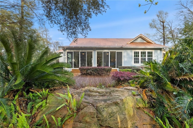 back of property featuring a sunroom and metal roof