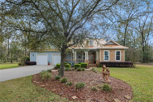 view of front of property with a front yard, driveway, a porch, a garage, and metal roof