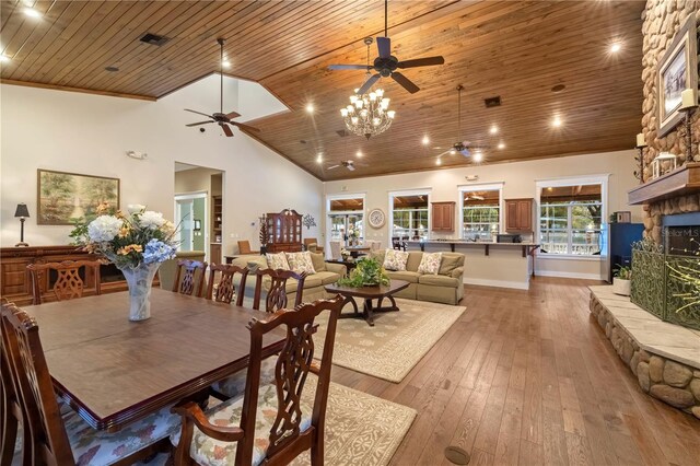 dining space featuring visible vents, wood ceiling, a stone fireplace, light wood-style flooring, and high vaulted ceiling