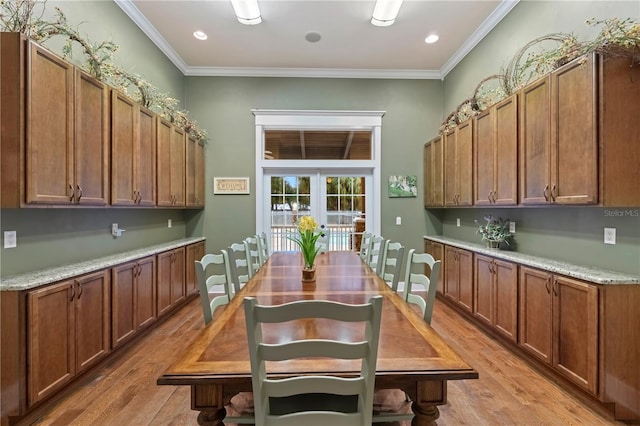 kitchen featuring light wood finished floors, recessed lighting, brown cabinets, and crown molding